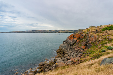 Fototapeta na wymiar Coastline with high cliff covered with rocks and colorful lichen