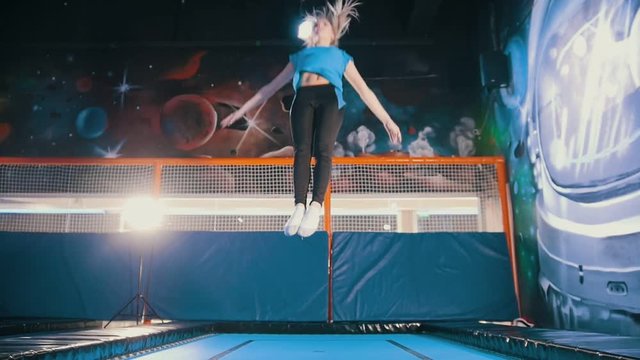 Young attractive athletic girl jumping on a trampoline in the sports centre, flying and doing tricks in the air