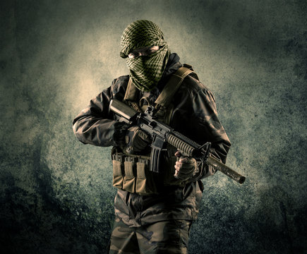 Portrait of a heavily armed masked soldier with grungy background