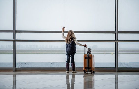 Small child flying to the destination. She is saying goodbye to the departing aircraft. Copy space in left side