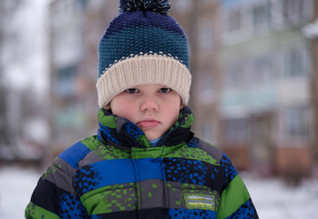 European boy with an emotion of resentment on the street in winter