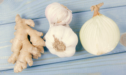 Garlic bulbs, ginger and onion on blue wooden table. Natural medicine.