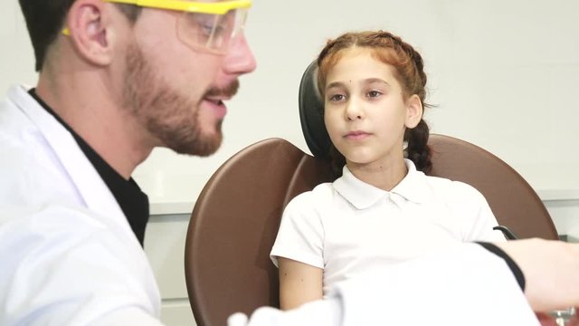 A kind doctor examines the teeth of a little girl