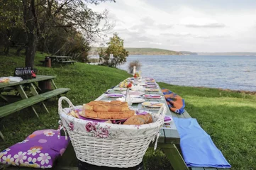 Foto auf Acrylglas Picknick Ein schicker Picknicktisch voller Essen am See im Frühling