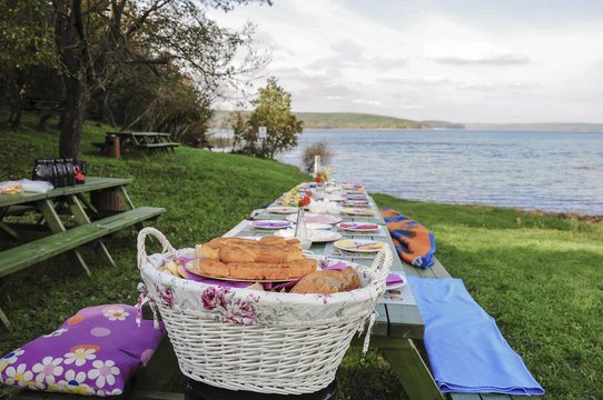 A fancy picnic table full of food by lake in spring