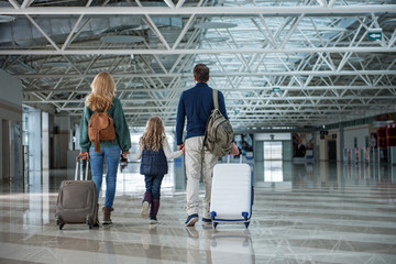 Mother, father and their little daughter arriving after long trip. They are going through airport...