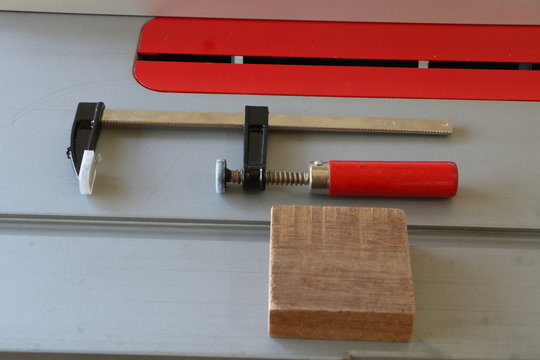F clamp with red handle on table saw, 

Using F clamp to hold wood in woodworking