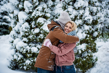 Fototapeta na wymiar Joyful friends are embracing after game with snow. They are standing in winter park and laughing