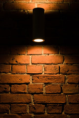 Lamp glowing light on old brick wall in the darkness.