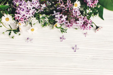 hello spring image. beautiful daisy  and lilac flowers with greenery on rustic white wooden background top view. space for text. greeting card. earth day. happy mothers woman day. eco.