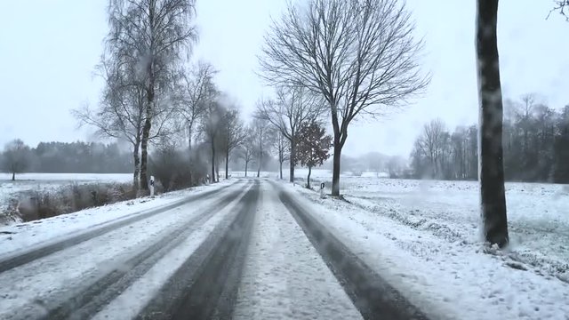 Auto fährt auf einer verschneiten Landstraße