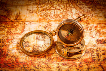 Vintage compass lies on an ancient world map.