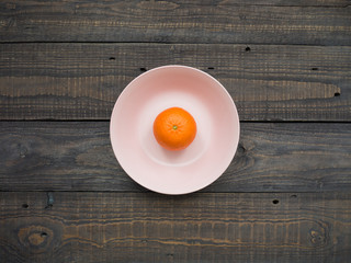 Ripe mandarin of large size in a plate on a wooden table