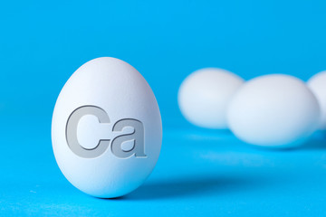 Chicken egg contains a lot of calcium Ca to strengthen bones and teeth. Eggs in a bowl on a blue background