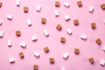 White and brown cane sugar cubes scattered on a pink background. Texture background