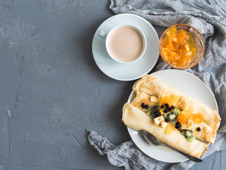 Strong, fragrant coffee and delicious pancakes, decorated with pieces of banana, kiwi and orange, soaked in maple syrup on a beautiful table