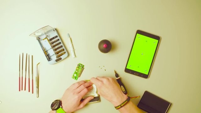 Top view. Green screen. Male hands reparing HDD and scrolling a tablet with green screen