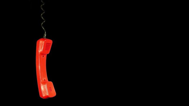 Swinging in the air bright red old rotary telephone handset hanging isolated against black background illustrate lost connection or other problem concept. Copy space for your text.