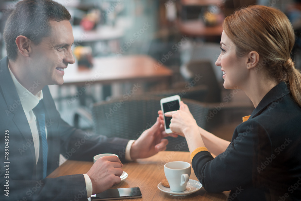 Aufkleber side view smiling woman showing on display of phone while telling with outgoing man. glad colleagues