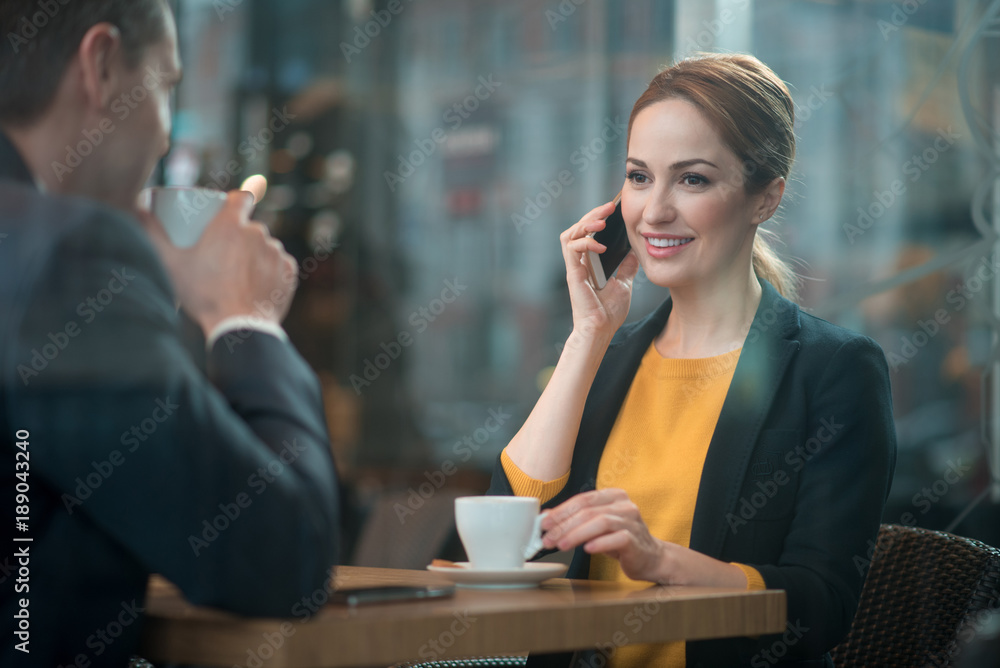 Aufkleber portrait of happy lady speaking by mobile while locating at desk with comrade. he drinking mug of be