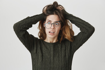 Portrait of young european girl with crazy expression, looking tired and depressed, wearing green...