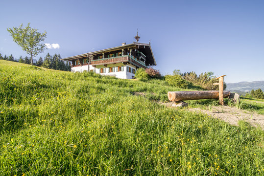 ein Bergbauer in Kitzb&uuml;hel im Fr&uuml;hling mit einem Brunnen vor dem Haus