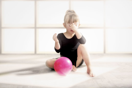 A Frustrated Little Gymnast Is Sitting With The Ball.