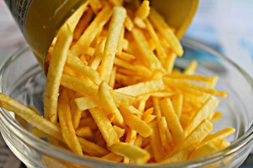 Pouring Delicious Yellow Fries Chips on a Plate, Closeup View of the Food