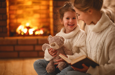 happy family mother and child daughter read a book on  winter evening