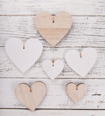 Heart composition for Valentine's, Mother's or Women's Day. Wooden hearts on old white desk.