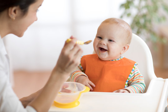 Young mother feeding her baby son with puree