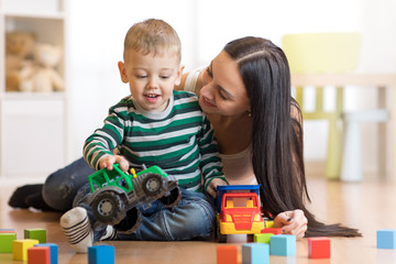 Mother and her toddler son plays with car in their living room