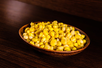 Ceramic plate with canned corn seeds on wooden table
