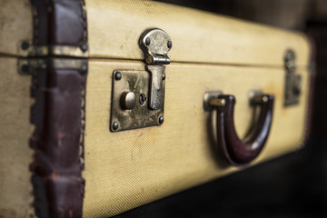 Old vintage hard yeallow suitcase with latch lock and handle torn and tattered leather trim