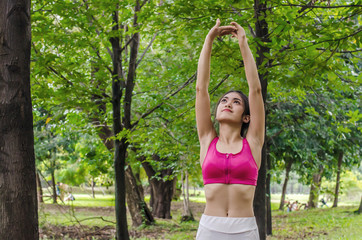 Female runner with beautiful figure doing stretching exercise in the park