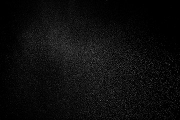 Freeze motion of white particles on black background. White granule explosion. Abstract white dust overlay texture.