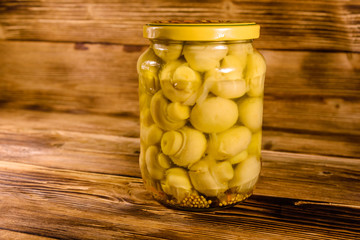 Jar with canned mushrooms on wooden table