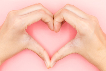 Female hands in the form of heart with Pink Pastel plastic texture background. Valentine concept. Minimal concept