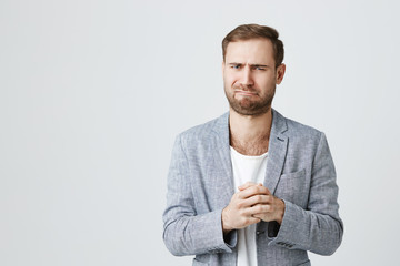 Portrait of good-looking stylish bearded male with disgusting expression of face, frowns in...