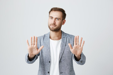 Good-looking bearded stylish man shows palms, demonstrates absence of responsibility, isolated...