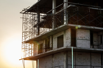 Building under construction, with the sun shining from behind the sun's rays with a silhouette.