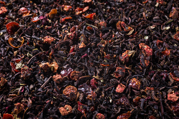 Food background with black tea, strawberry pieces and rose blossom with copy space. Selective focus.