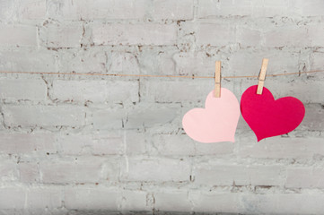 Two hearts  on clothespins against a brick wall background