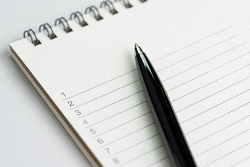 Personal to do lists or new year's resolution concept by closed up of list of numbers on white clean notepad with pen on it