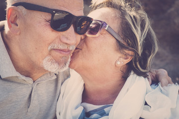 two seniors with sunglasses kiss themselves
