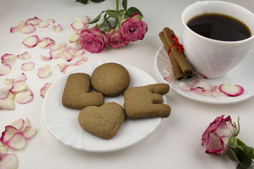 .An inscription from a love cookie, black coffee, rose petals on a white background