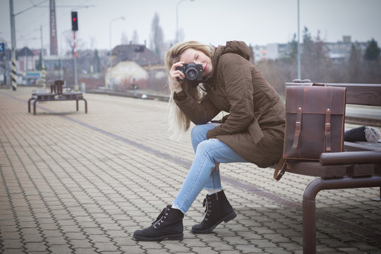 young blonde woman taking picture on train station