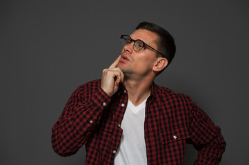 Thoughtful man, a teacher with glasses thinks about something on gray background