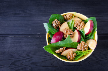 Spinach salad with nuts and apples served on table