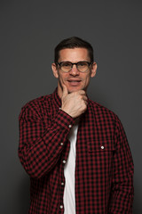 Fototapeta premium Close-up portrait of handsome positive young man with glasses and formal clothes looking at the camera on gray background